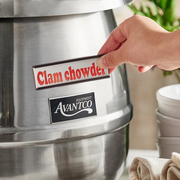 A person using an Avantco stainless steel soup kettle to serve clam chowder on a hotel buffet counter.