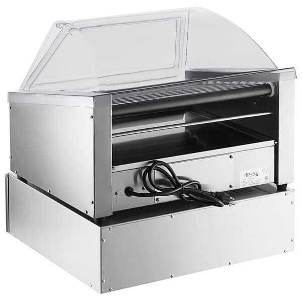 An Avantco slanted silver hot dog roller with a clear sneeze guard over it.