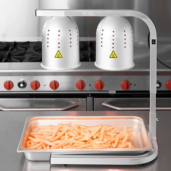 An Avantco countertop heat lamp with red bulbs keeping french fries warm.