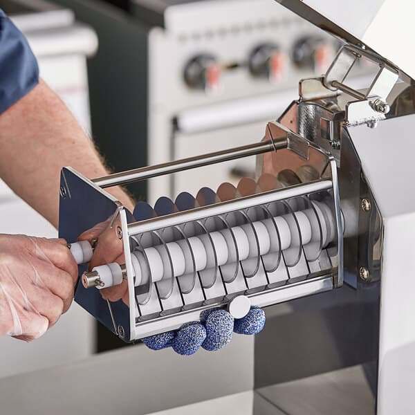 A person using a tool to cut a piece of metal with an Avantco Meat Stripper Blade Set.