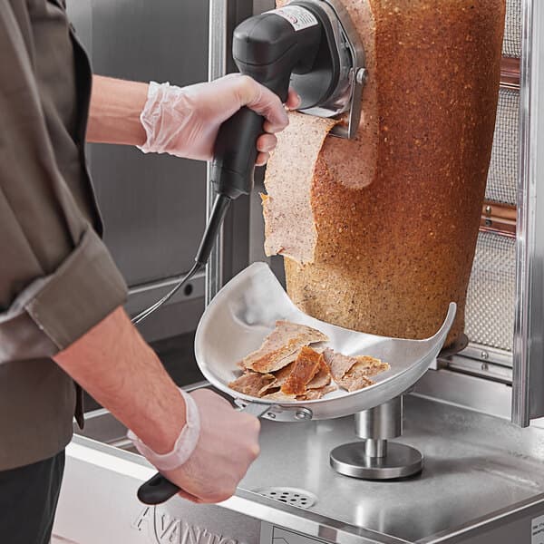 A person using an Avantco kebab slicer to cut meat.