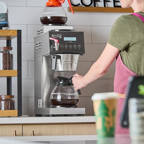 A digital automatic coffee maker with two upper and one lower decanter warmers being used in a café setting.
