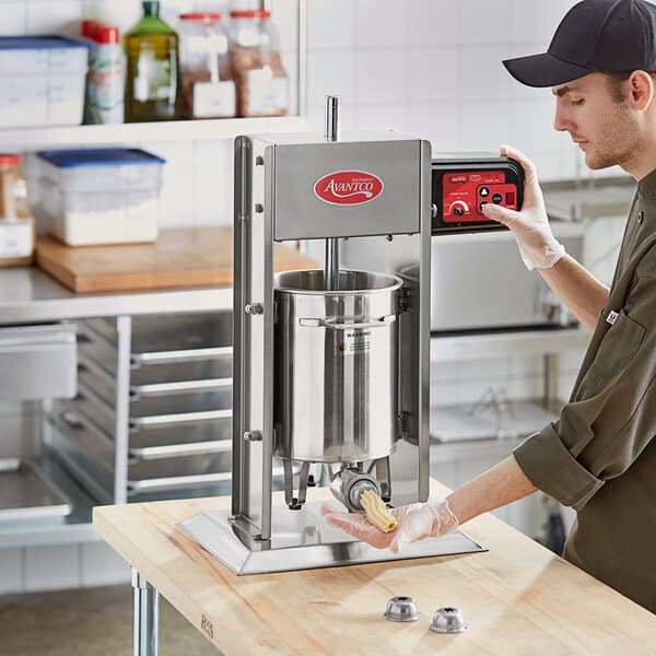 A man using an Avantco stainless steel churro stuffer on a counter in a professional kitchen.