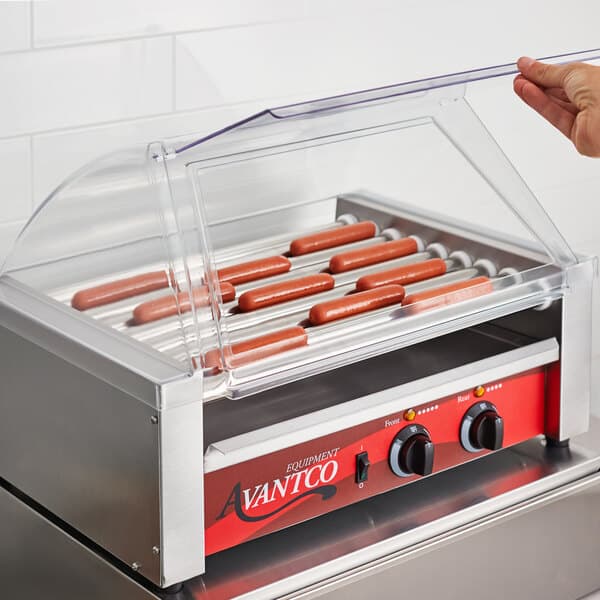 A hand placing a hot dog on an Avantco hot dog roller grill.