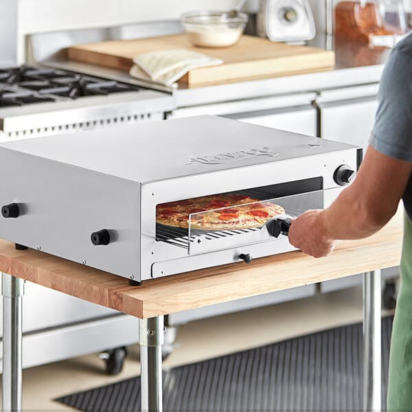 A man putting a pizza in an Avantco countertop pizza oven.