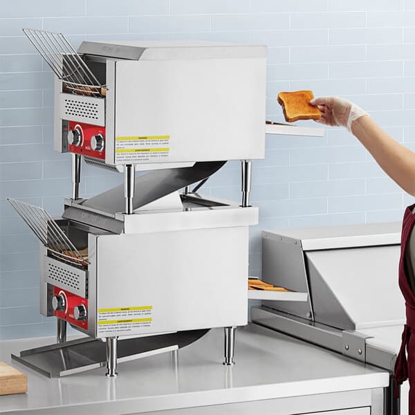 A woman in a red apron using an Avantco conveyor toaster to make toast.