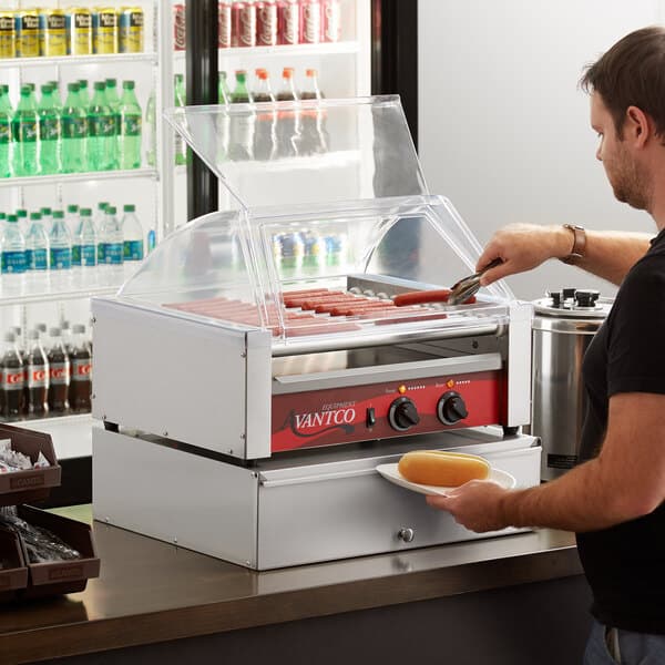 A man preparing hot dogs on an Avantco hot dog roller.