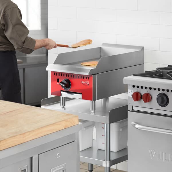A man using an Avantco countertop gas griddle to cook food in a professional kitchen.