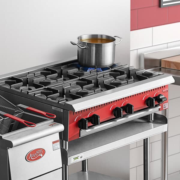 An Avantco red gas countertop range with a pot on top.