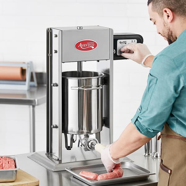 A person using an Avantco stainless steel sausage stuffer to fill meat.