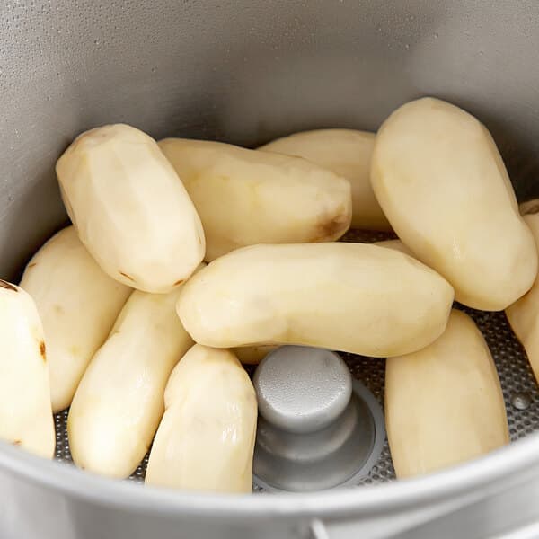 White potatoes being peeled in an Avantco floor potato peeler.