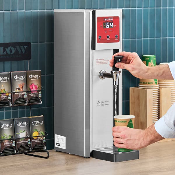 A stainless steel hot water dispenser with digital controls being used to fill a paper cup.