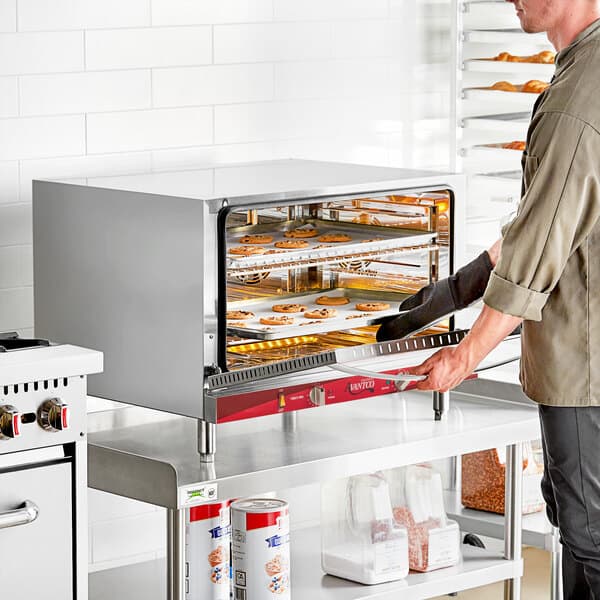 A man using an Avantco countertop convection oven to cook food.