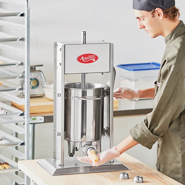 A man using an Avantco stainless steel vertical churro stuffer.