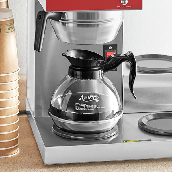 An Avantco coffee decanter with a stainless steel bottom and black handle on a counter.