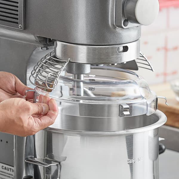A person using an Avantco mixer with a splash cover.