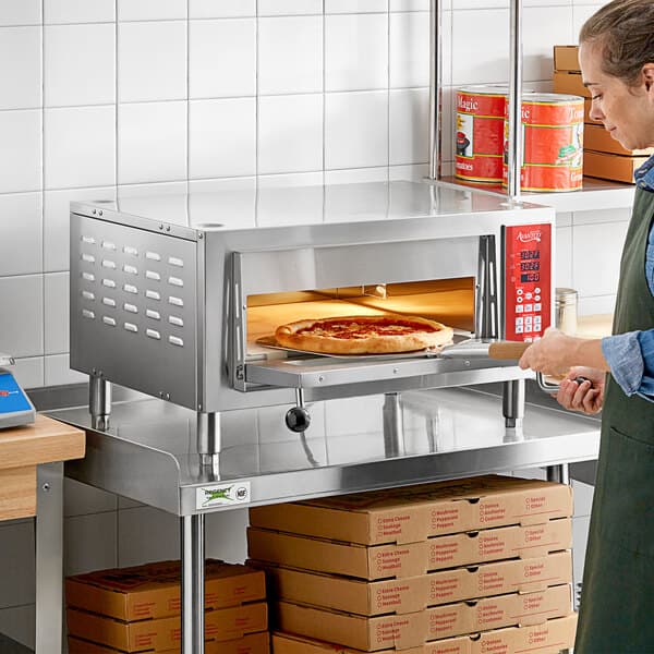 A woman using an Avantco countertop pizza oven in a kitchen.