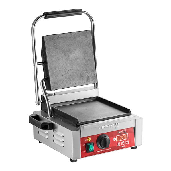 An Avantco commercial panini grill with smooth plates on a table in a professional kitchen.