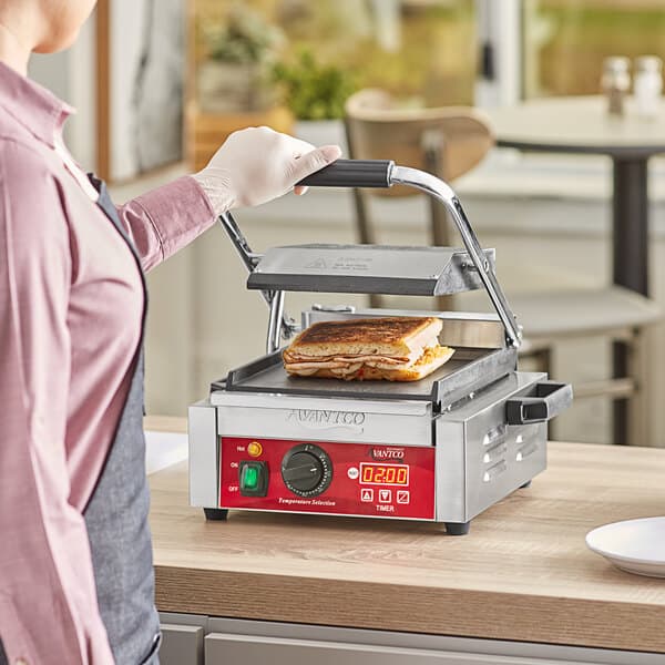 A woman using the Avantco Commercial Panini Grill to make a sandwich.
