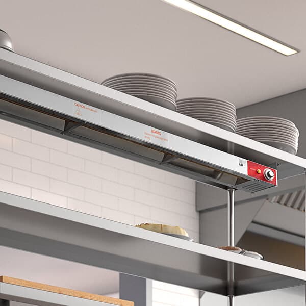 An Avantco strip warmer with plates on a stainless steel shelf.