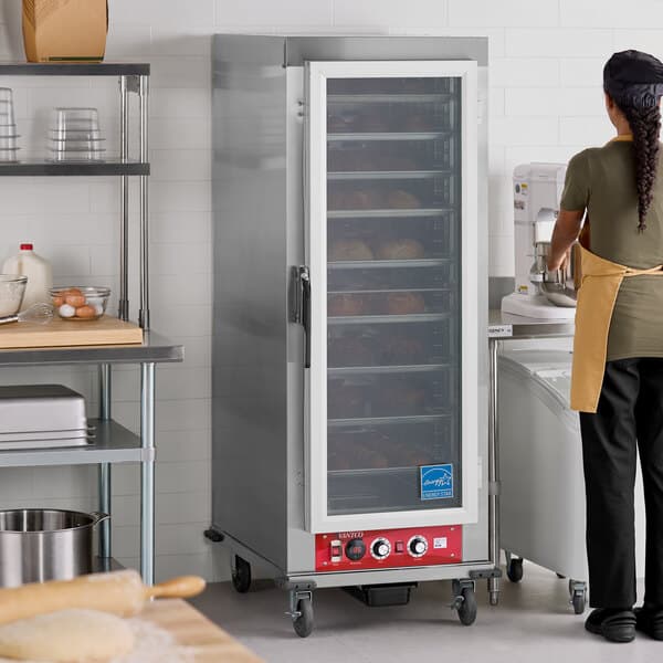 A full size vacuum-insulated heated holding and proofing cabinet with a clear door on casters.