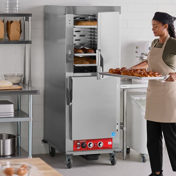 A full size insulated heated holding and proofing cabinet with solid stainless steel Dutch doors in a commercial kitchen setting.