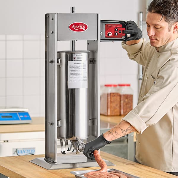 A man using an Avantco stainless steel vertical sausage stuffer on a counter.